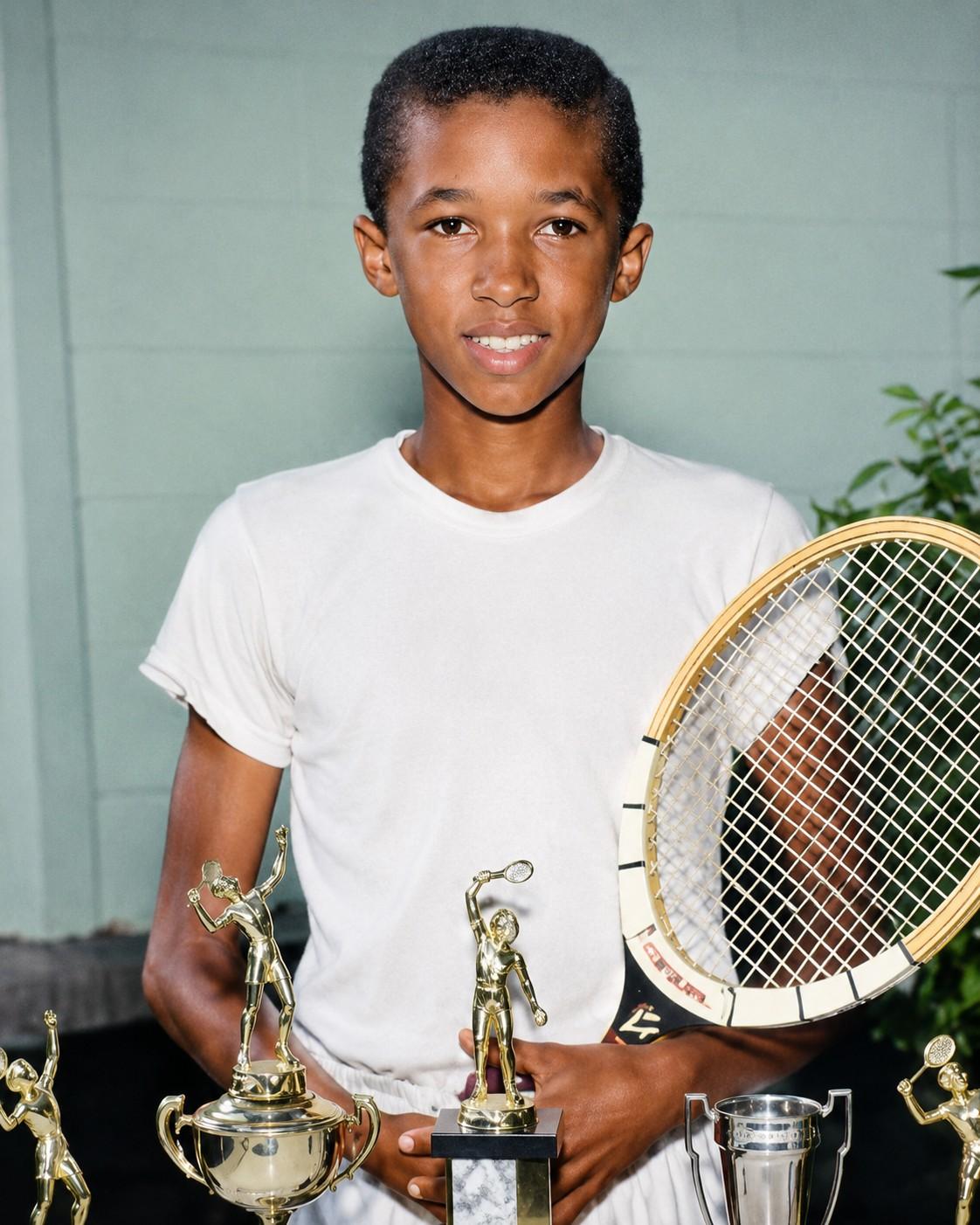 Arthur Ashe enfant avec une raquette et ses trophées